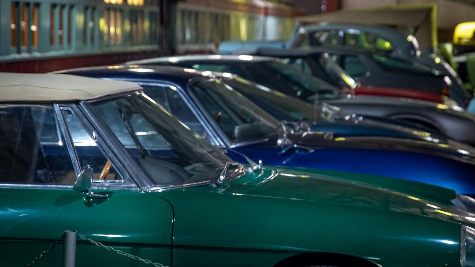 Eine Reihe dicht geparkter Klassiker, vorn ein dunkelgrünes Coupé