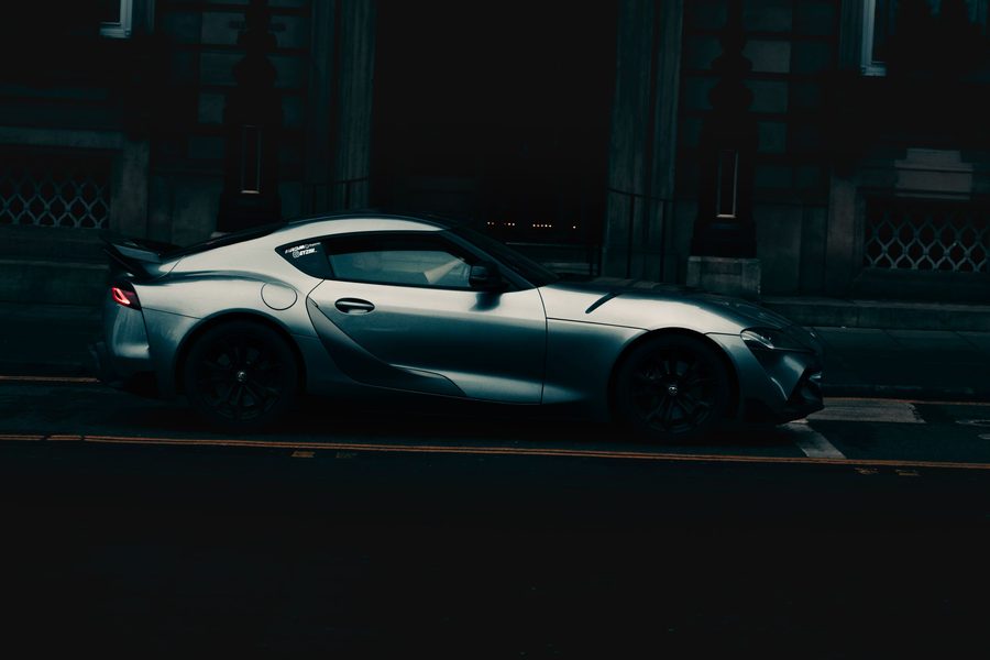 Dunkles Sportcoupé bei Nacht vor einer Steinfassade